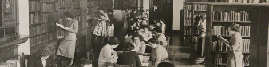 Old black and white photo of group of people in a library